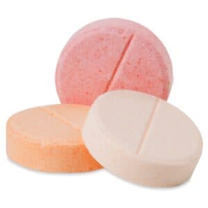 Three assorted glucose tablets in orange, pink, and white used for quick low blood sugar relief in Type 1 Diabetes.
